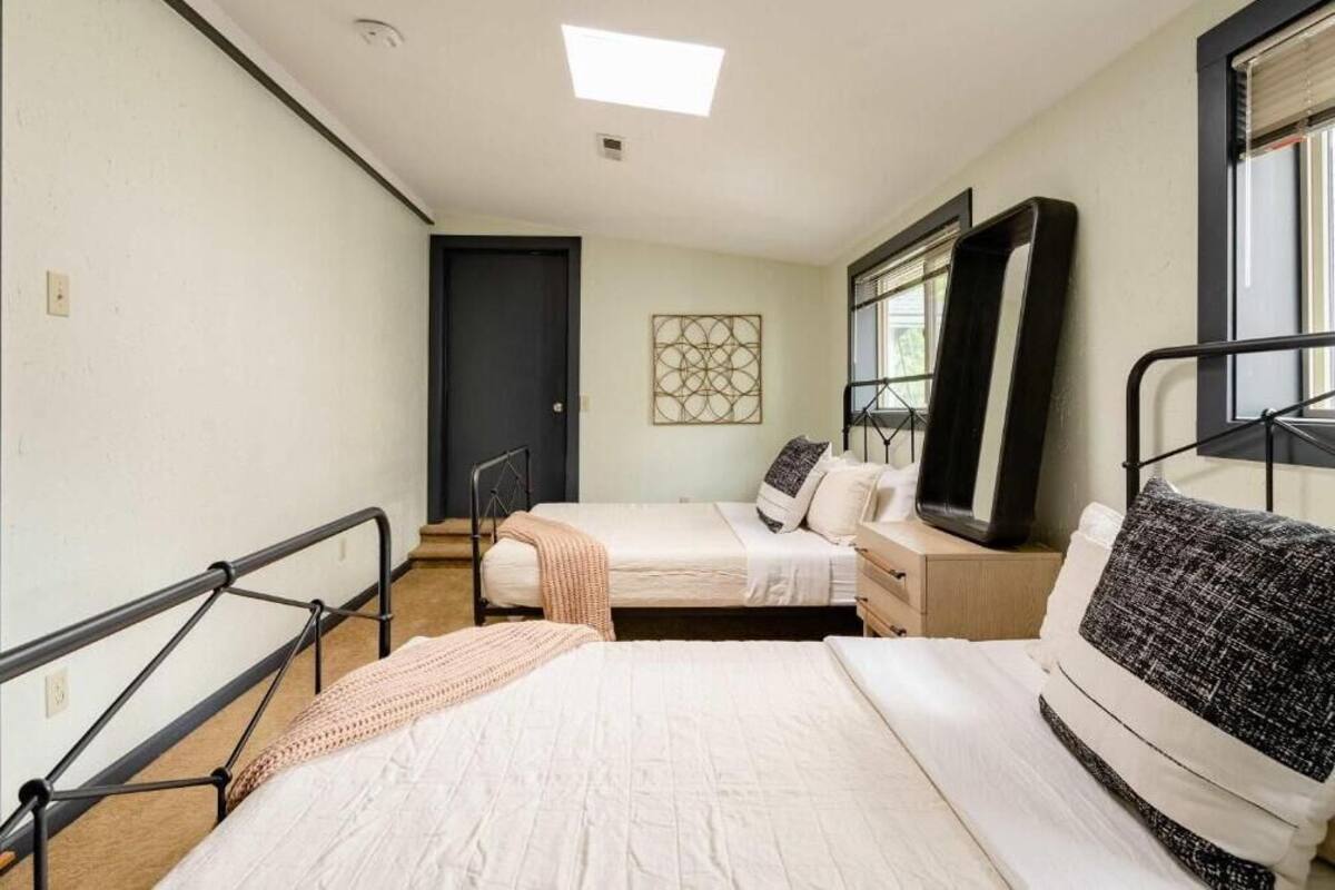 Un dormitorio con dos camas, una ventana, una puerta y una lámpara en el techo.