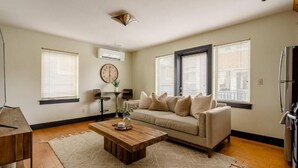 A living room with a sofa, coffee table, and a clock on the wall.
