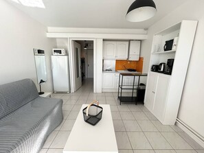 Ein kleiner Wohnbereich mit Küchenzeile, einer Couch und einer Kaffeemaschine.