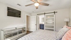 A bedroom with a bed, a ceiling fan, a TV, a dresser, a sliding door, and a window. - Quiet Furnished 2-Acre Retreat for Medical, Corporate & Family Stays (Manvel)