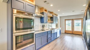 A modern kitchen with built-in ovens, a sink, and a large window. - Quiet Furnished 2-Acre Retreat for Medical, Corporate & Family Stays (Manvel)