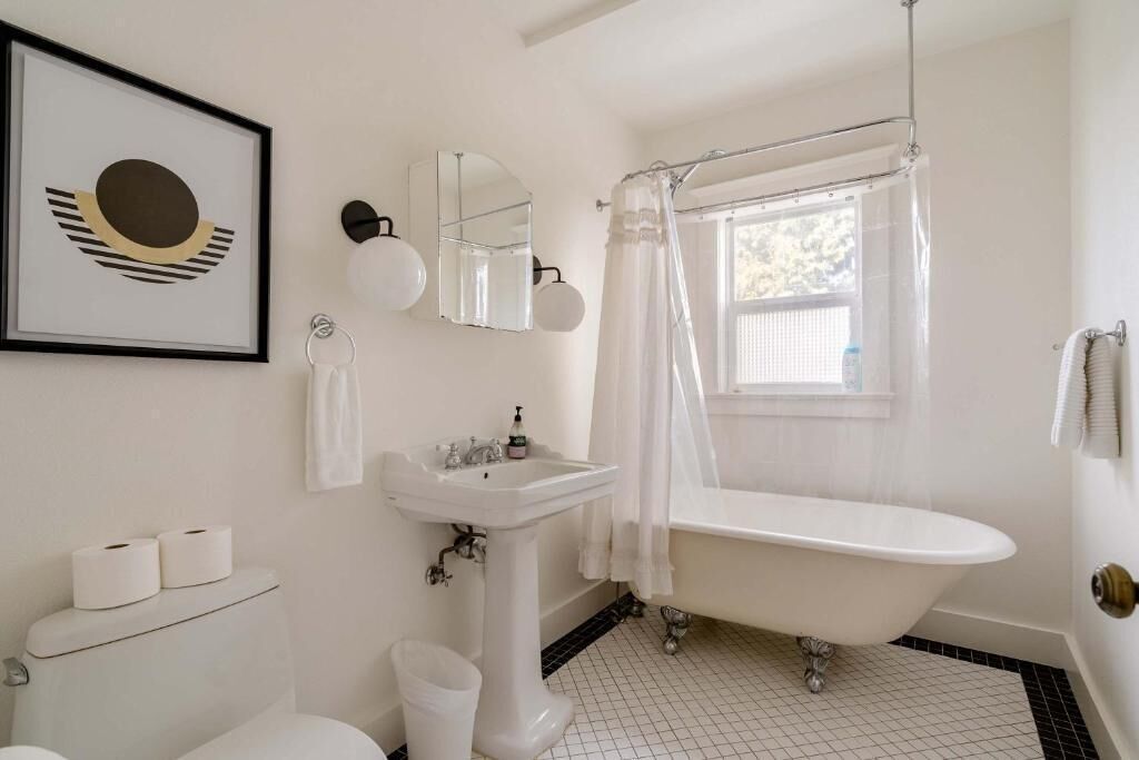 A bathroom with a white toilet, pedestal sink, and clawfoot bathtub.