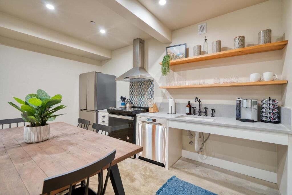 A modern kitchen with a dining table, chairs, a coffee machine, and a dishwasher.