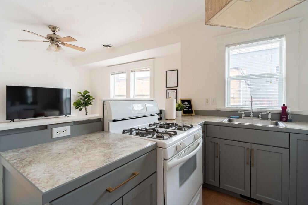 A kitchen with a gas stove, oven, and a TV on the counter.