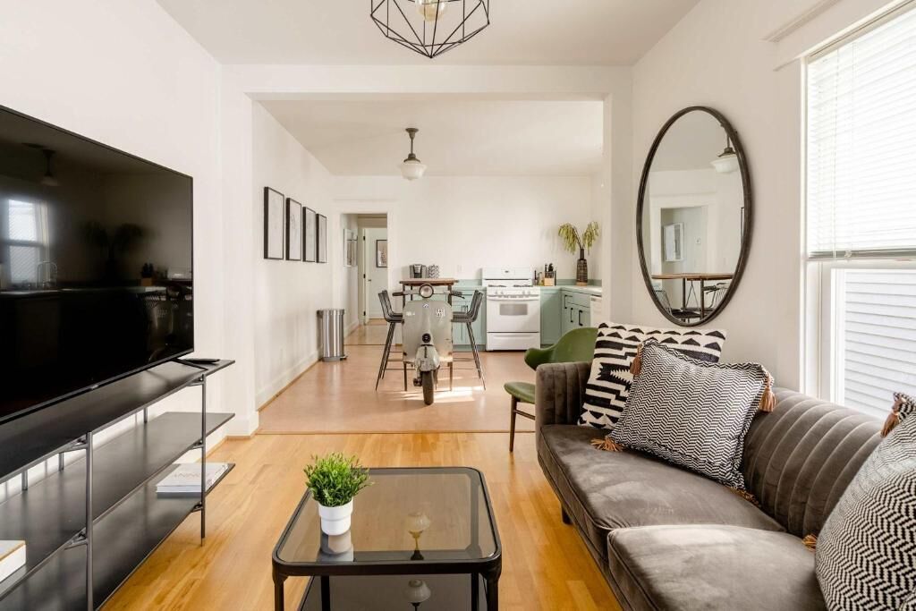 Un salon avec un téléviseur, un canapé, une table basse et, au fond, un coin repas.