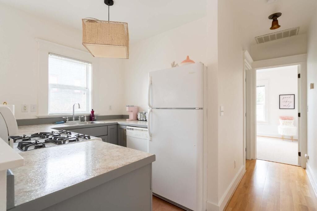 A kitchen with a gas stove, white refrigerator, and a window.