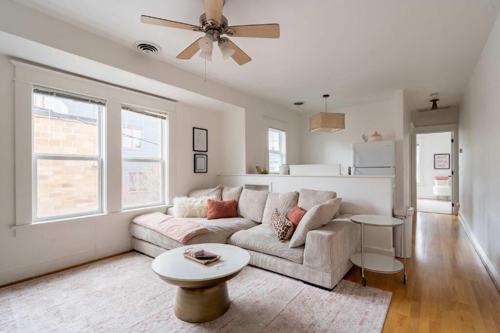 A modern living room with a sofa, a coffee table, and a ceiling fan.