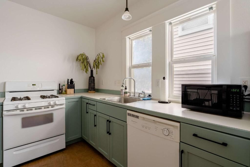 A kitchen with a stove, sink, dishwasher, and microwave.