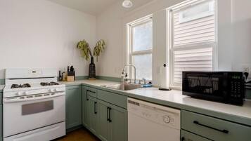 Una cocina equipada con estufa, lavaplatos, fregadero y microondas.