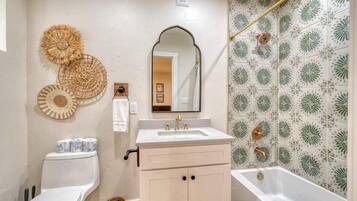 A bathroom with a toilet, sink, vanity, and bathtub.