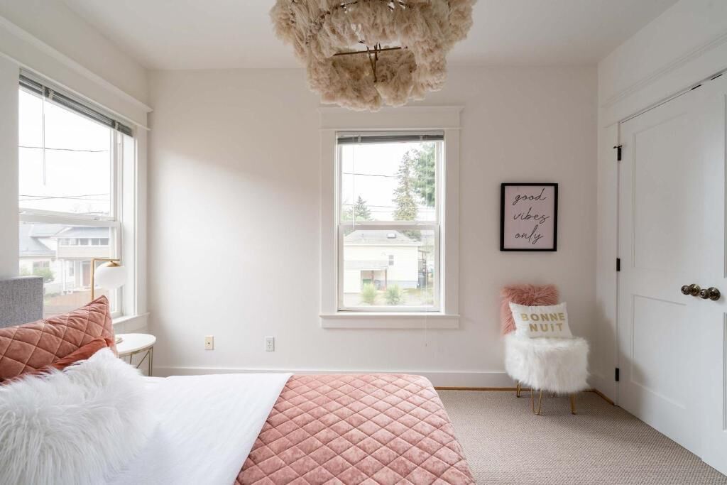 A bedroom with a bed, a window, a chair, and a door.