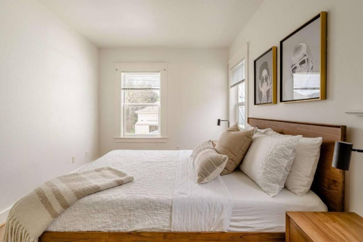 A bedroom with a bed, a window, and two framed pictures on the wall.