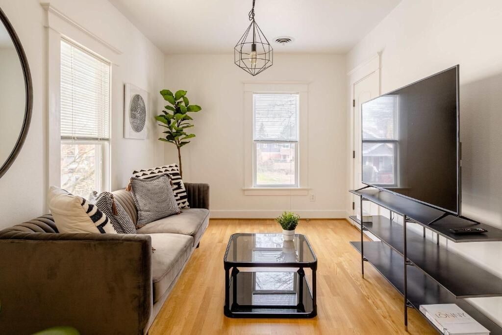 A living room with a sofa, a coffee table, a TV, and a plant.