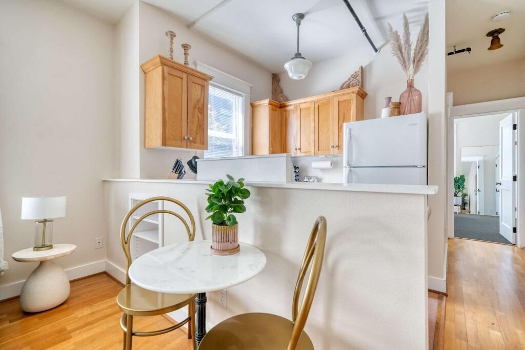 A kitchen with wooden cabinets, a white refrigerator, a marble table, and two chairs.