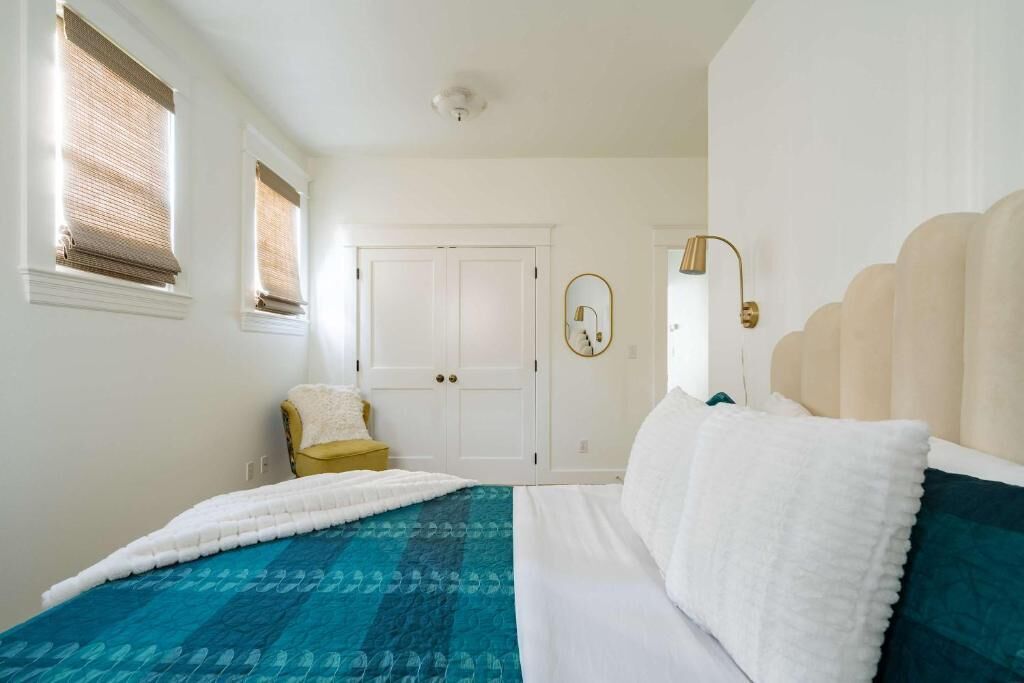 A bedroom with a bed, a chair, a wardrobe, and a mirror.