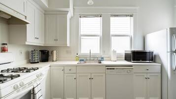 A kitchen with white cabinets, a stove, a microwave, and a dishwasher.