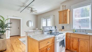 A kitchen with wooden cabinets, a stove, and a window with blinds.