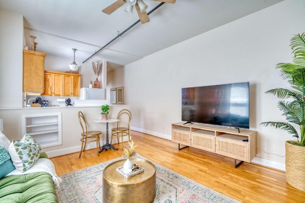 A modern living room with a sofa, coffee table, TV, and kitchen area.