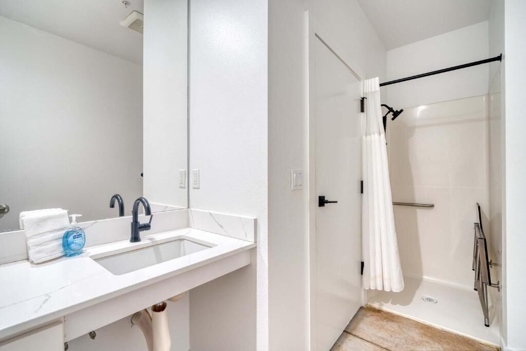A bathroom with a white sink, mirror, and shower area.