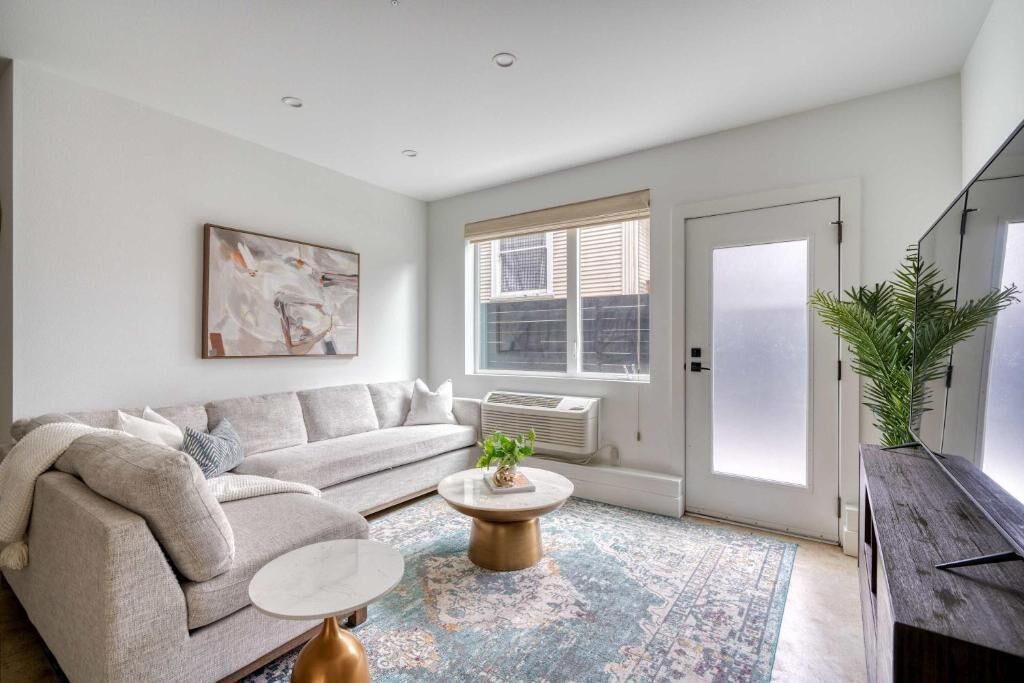 A living room with a sofa, coffee table, and a large window with blinds.