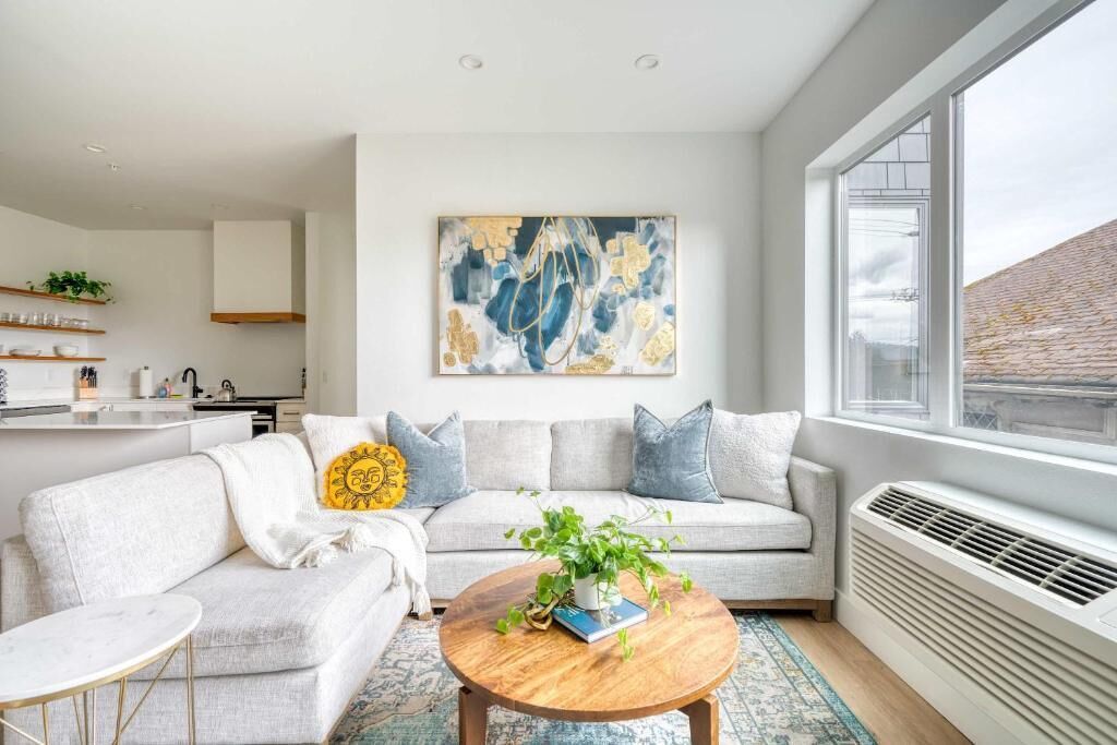 A modern living room with a sofa, coffee table, and a large abstract painting.