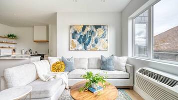 A modern living room with a sofa, coffee table, and a large abstract painting.