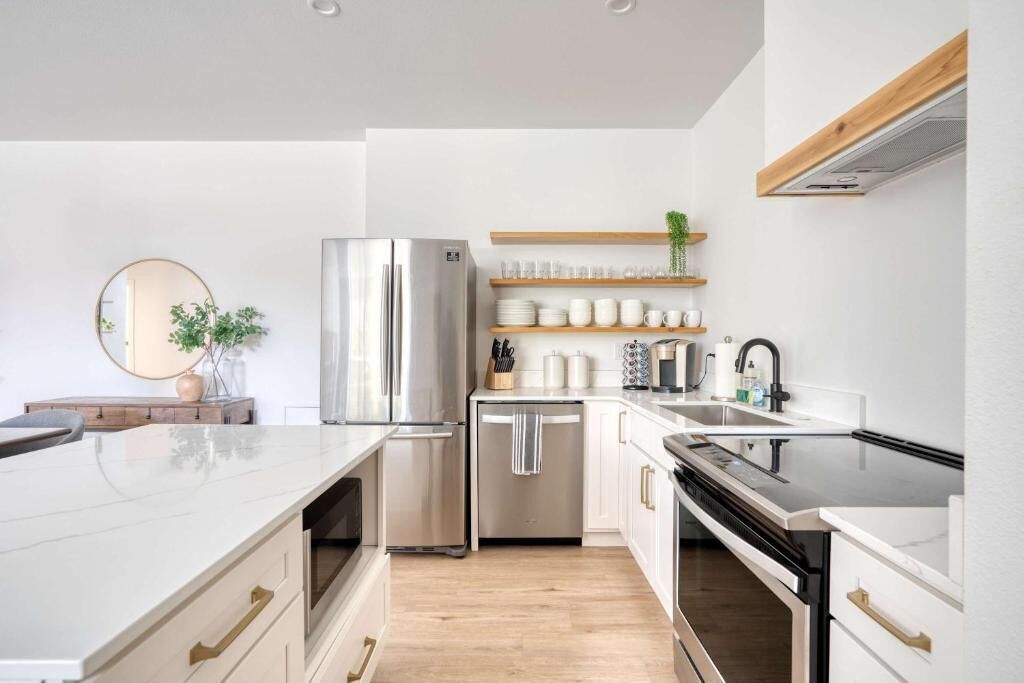 A modern kitchen with a stainless steel refrigerator, a dishwasher, and a countertop with various kitchen items.