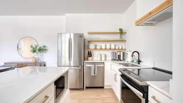 Una cocina moderna con un refrigerador de acero inoxidable, un lavavajillas y una encimera con diversos utensilios de cocina.