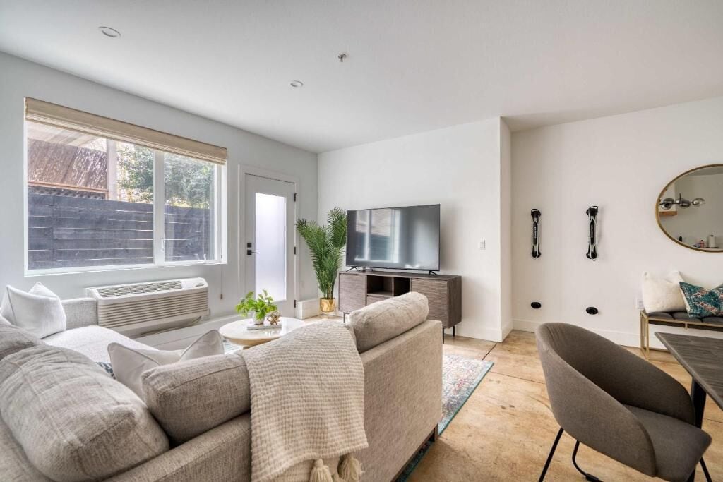 A modern living room with a sofa, TV, and a dining area.
