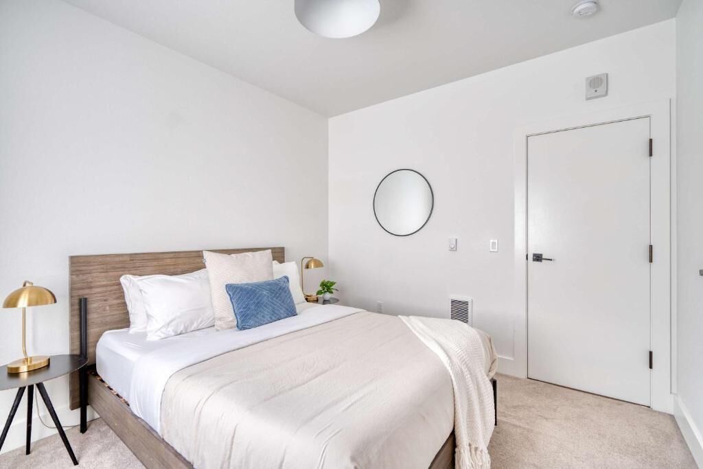 A bedroom with a bed, bedside table, lamp, and a door.