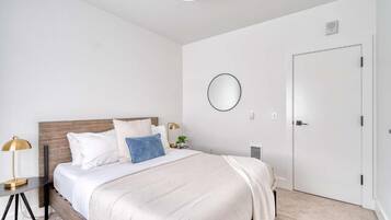 A bedroom with a bed, bedside table, lamp, and a door.