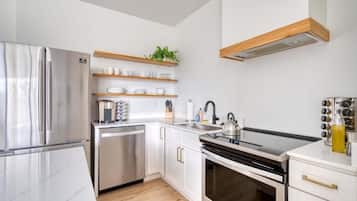 A modern kitchen with stainless steel appliances, wooden shelves, and a built-in oven.