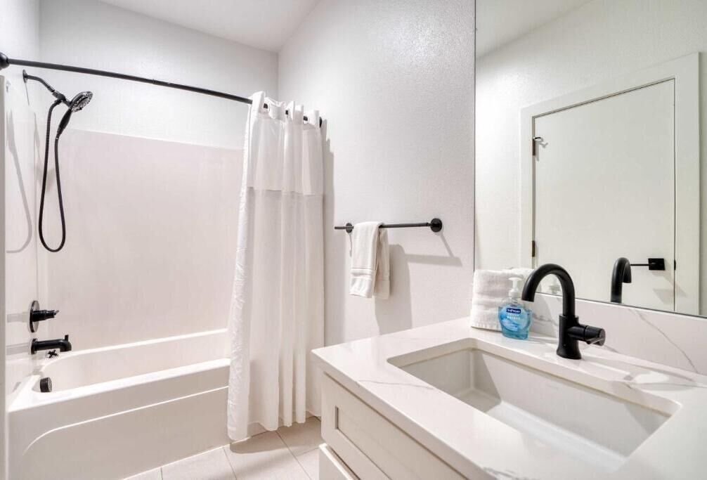 Une salle de bain avec une baignoire, une douche, un lavabo et un miroir.