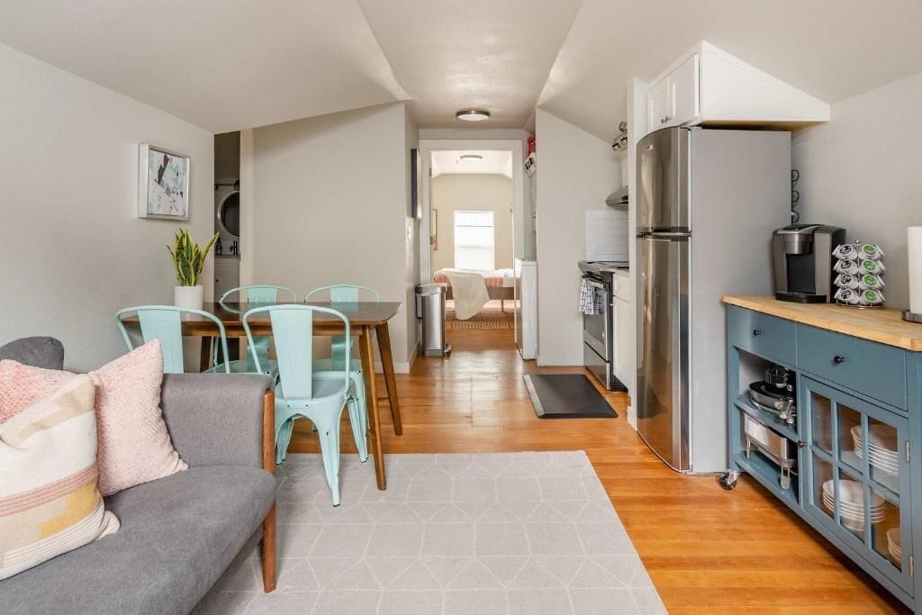 Un espacio habitable compacto con kitchenette, una zona de comedor con mesa y sillas, y un sofá.