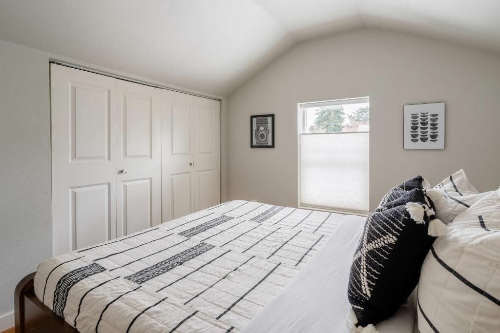 Een slaapkamer met een bed, een raam, een deur en een aan de muur hangend schilderij.