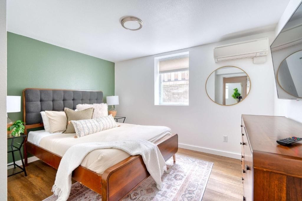 A bedroom with a bed, bedside tables, a dresser, a mirror, and a window.