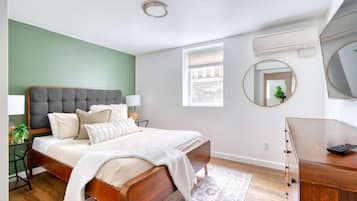 A bedroom with a bed, bedside tables, a dresser, a mirror, and a window.