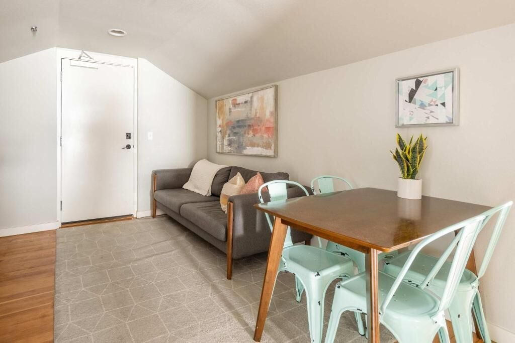 A modern living room with a sofa, a dining table, and two chairs.