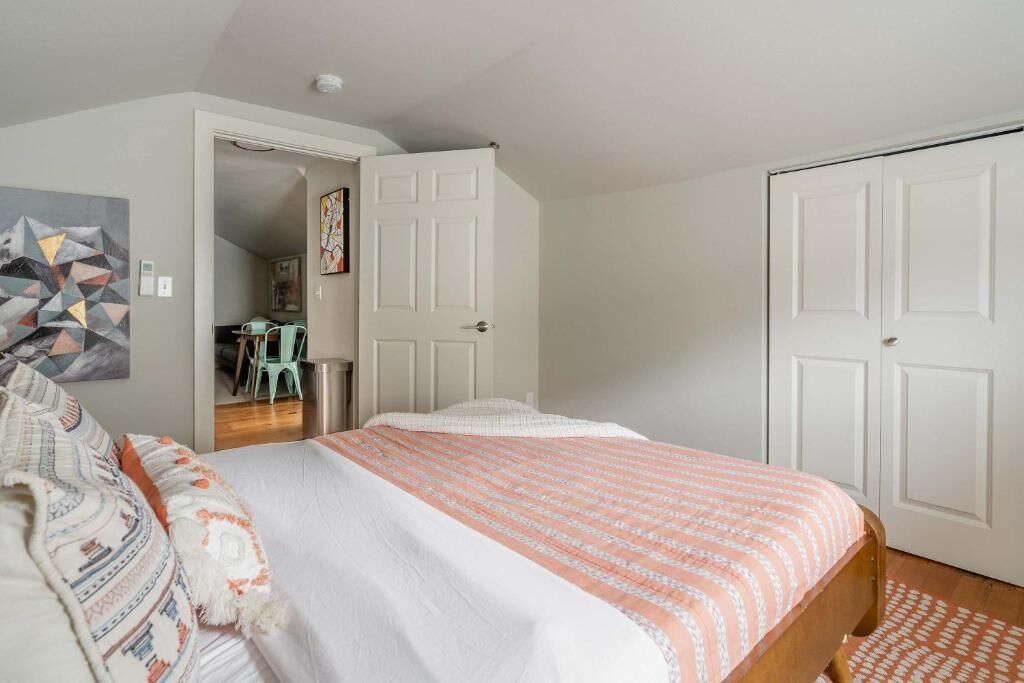 A bedroom with a bed, a door, and a wall with a geometric painting.