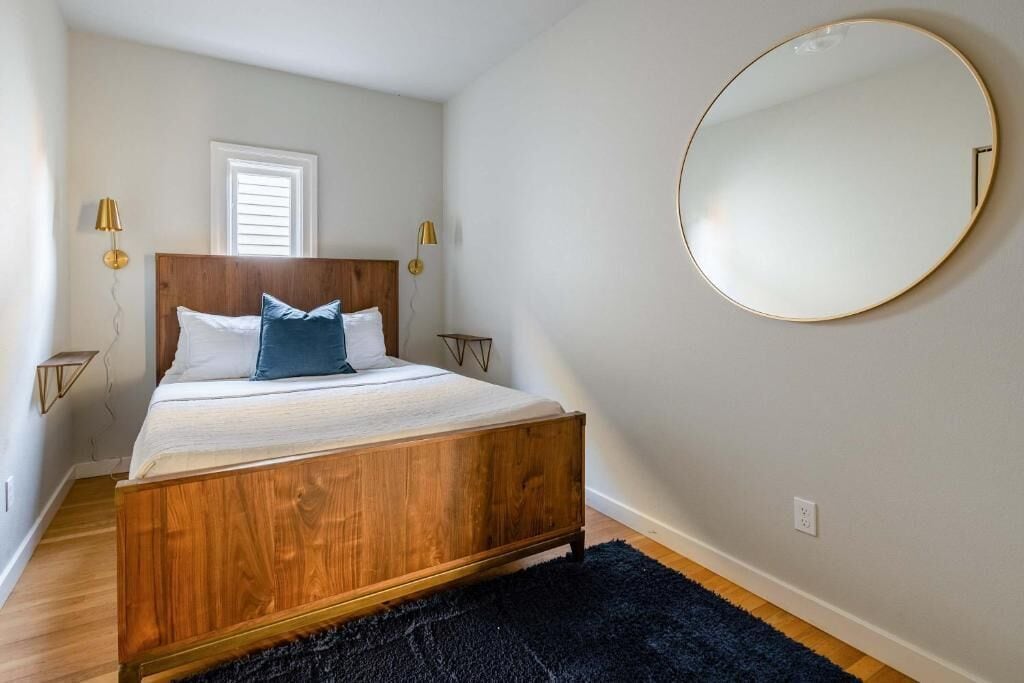Una camera da letto con un letto in legno, uno specchio tondo e due lampade ai comodini.