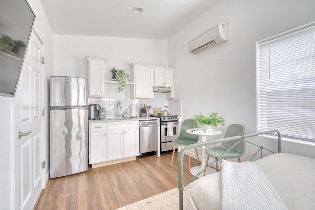 A compact kitchen with white cabinets, stainless steel appliances, and a dining area with a small table and chairs.