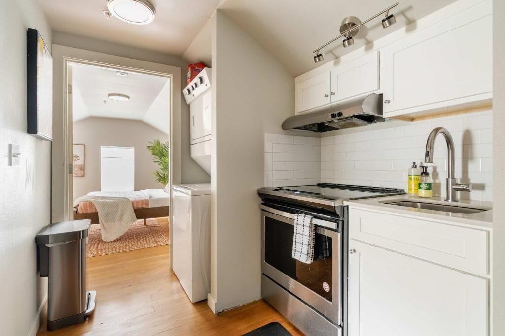 A compact kitchen with white cabinets, a stainless steel stove, and a sink.