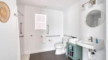A bathroom with a toilet, sink, and shower area.