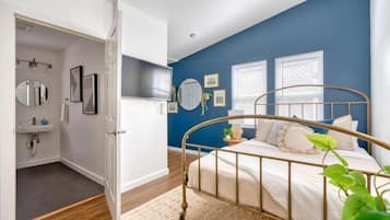 Un dormitorio con cama, mesita de noche, espejo y ventana con persianas.