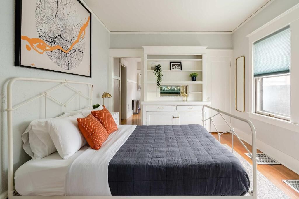 Une chambre à coucher avec un lit, des murs blancs, une fenêtre, un bureau et une chaise.