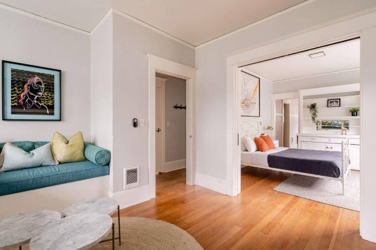 Un interior moderno con un sofá, una cama, una mesa de comedor y un pasillo que conduce a otra habitación.