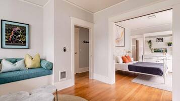 A modern interior with a sofa, a bed, a dining table, and a hallway leading to another room.