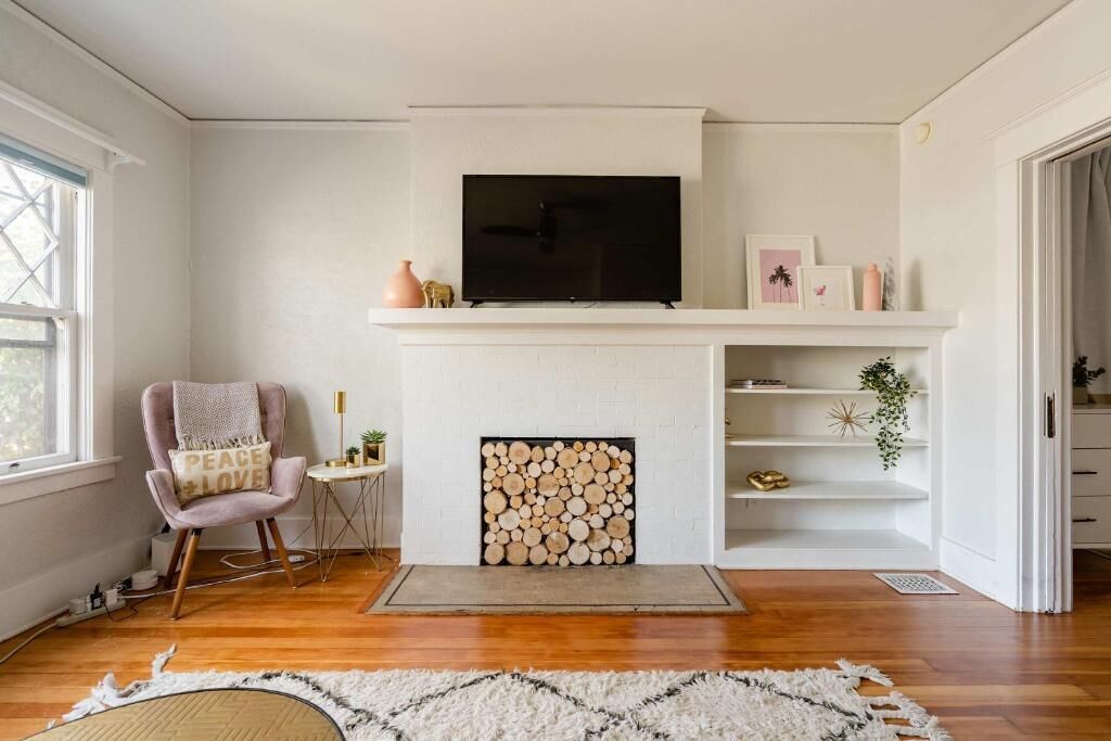 Un salon avec une cheminée, un téléviseur, un fauteuil et un tapis.