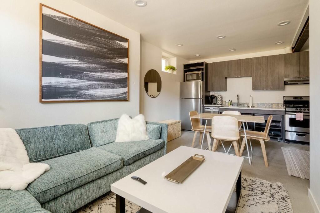 Een moderne woonkamer met een bank, salontafel en een eethoek met stoelen en een tafel.