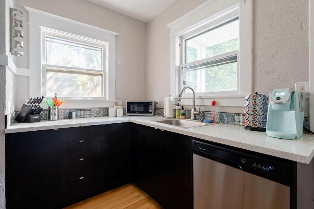 A kitchen with black cabinets, a microwave, a coffee maker, and a dishwasher.